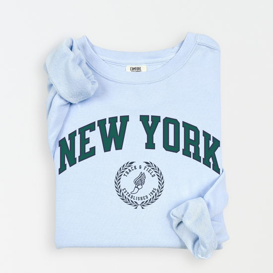 A Comfort Colors lightweight cotton crewneck sweatshirt with "New York Track & Field" printed in vintage retro style, giving a refined old money look.