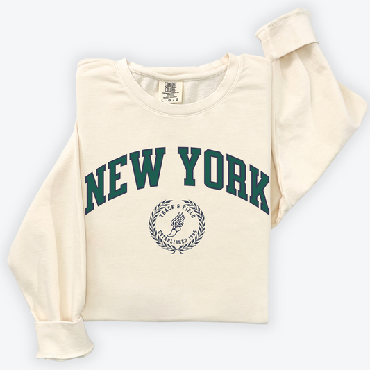 A Comfort Colors lightweight cotton crewneck sweatshirt with "New York Track & Field" printed in vintage retro style, giving a refined old money look.