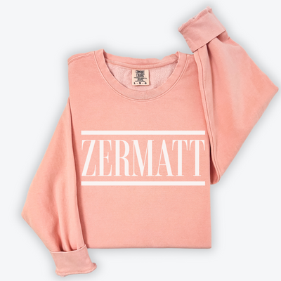 Flatlay image of a lightweight Comfort Colors crewneck sweatshirt with 'Zermatt' design, featuring vintage après-ski vibes. The sweatshirt has a soft, relaxed fit with a worn-in, nostalgic look, perfect for post-ski relaxation or everyday casual wear.