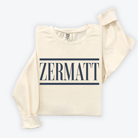 Flatlay image of a lightweight Comfort Colors crewneck sweatshirt with 'Zermatt' design, featuring vintage après-ski vibes. The sweatshirt has a soft, relaxed fit with a worn-in, nostalgic look, perfect for post-ski relaxation or everyday casual wear.