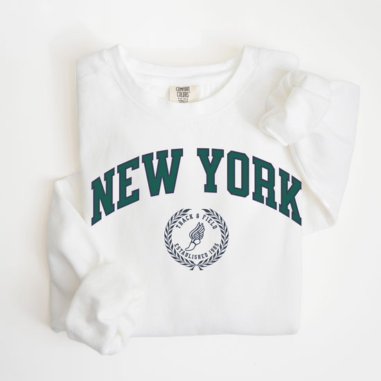 A Comfort Colors lightweight cotton crewneck sweatshirt with "New York Track & Field" printed in vintage retro style, giving a refined old money look.